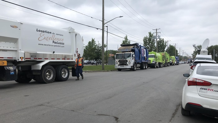 Des camions de collecte des ordures font la file en bordure du boulevard Montmorency.