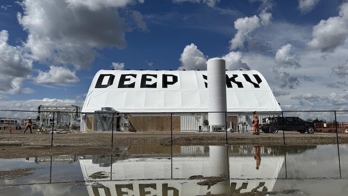 Le bâtiment de l'entreprise Deep Sky qui se reflète dans une étendue d'eau, en Alberta, en mai 2025.