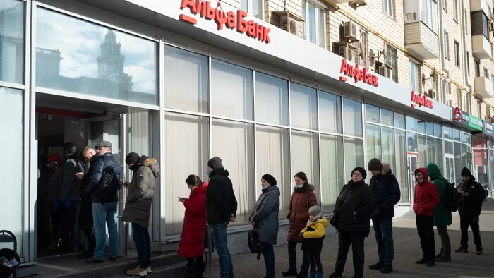 People stand in line to withdraw money from an Alfa Bank ATM in Moscow, Russia on Feb. 27, 2022. Russians flocked to banks and ATMs shortly after Russia launched an attack on Ukraine and the West announced crippling sanctions.