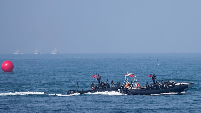 Deux vedettes militaires sur l'eau, avec en arrière-plan trois navires.