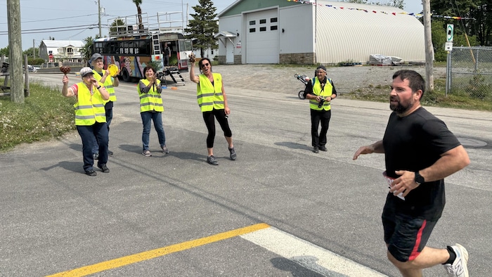 Cinq personnes qui portent des vestes de sécurité encouragent un coureur.