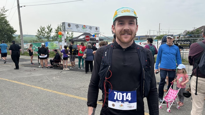 Un jeune homme en vêtements de course numéroté sourit pour la photo.