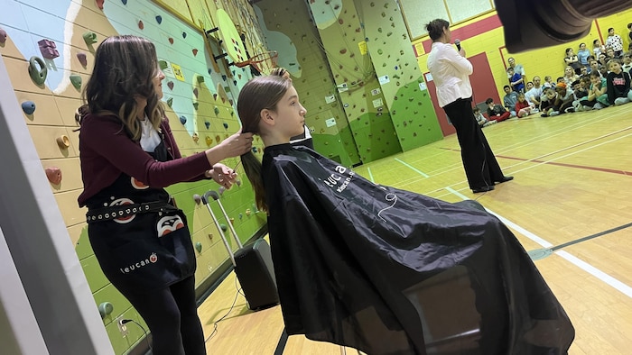Une femme tient les cheveux d'un garçon dans un gymnase.