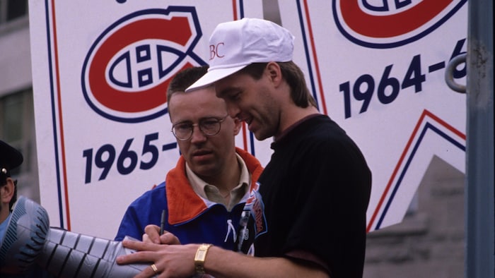 François Allaire, entraîneur des gardiens de but, observe le gardien Patrick Roy qui signe une reproduction de la Coupe
Stanley durant le défilé sur la rue Sherbrooke.
