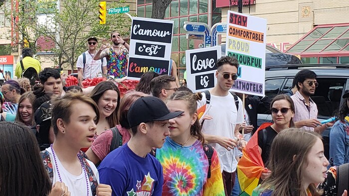 Des jeunes portent des pancartes lors du défilé de la Fierté 2019 à Winnipeg.