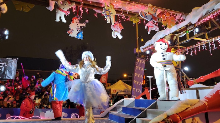 Une femme danse sur une scène aux côtés de bonhomme. 