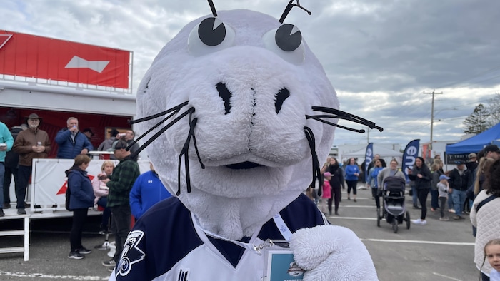 La mascotte tient sa passe dans son cou.