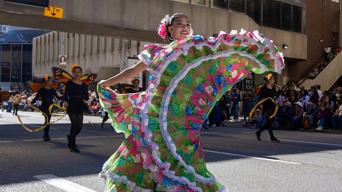 Une femme fait virevolter la jupe de sa grande robe multicolore.