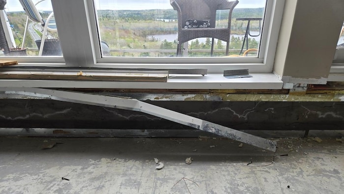 Une barre de métal s'est décrochée du mur et des débris de platres sont éparpillés au bord de la fenêtre.