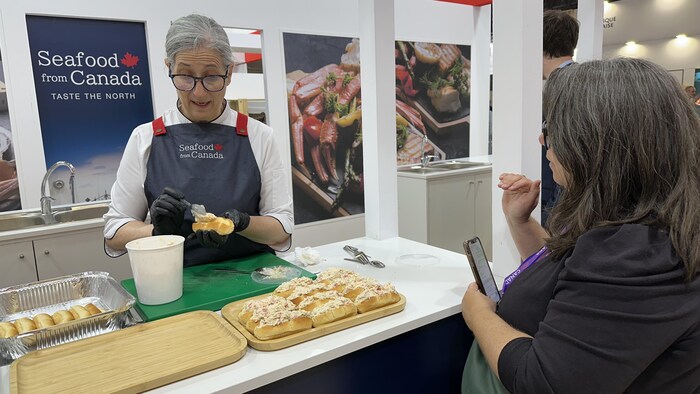 Une femme prépare une guédille au homard.