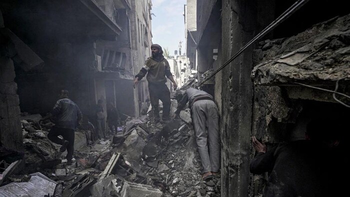 Des Palestiniens fouillent les décombres d'un immeuble en ruine.
