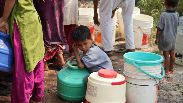A young boy, one of thousands of displaced Rohingya children who can't get a proper education, waits in a long line for clean water to take back to the makeshift refugee camp in New Delhi, which has no toilets or running water. (Salimah Shivji/CBC)