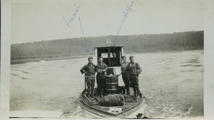 Une photo d'époque en noir et blanc montre cinq personnes sur une embarcation motorisée sur une rivière.