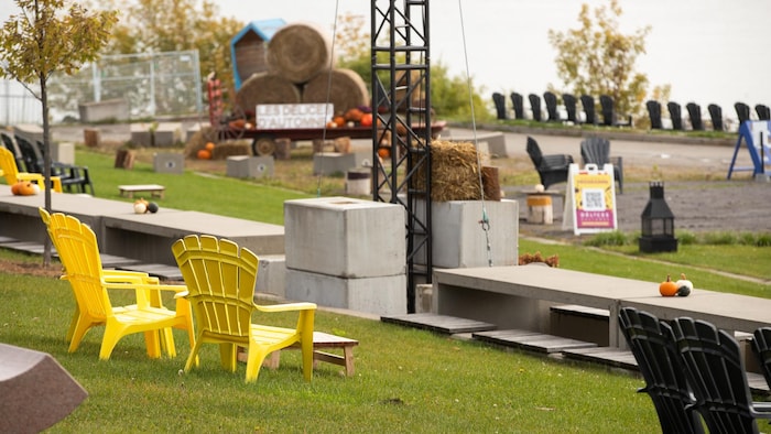 Des chaises adirondack sur le gazon face au fleuve.
