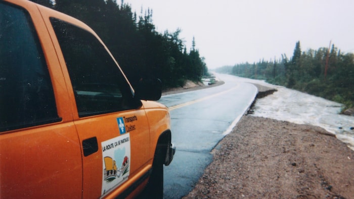 Une voiture sur le bord de la route presque inondée.