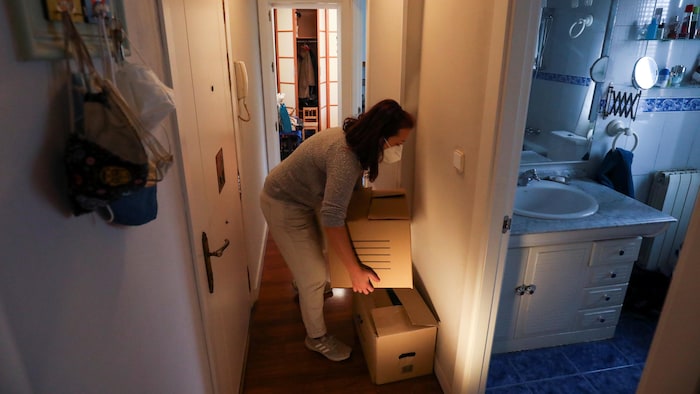 Une femme déplace des boîtes dans son appartement.