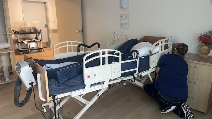 Un membre du personnel de la Villa Providence installe un lit médicalisé.