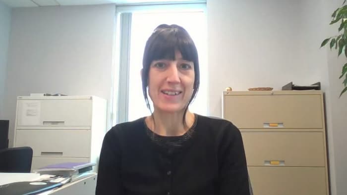 Une femme dans un bureau parle à la caméra.