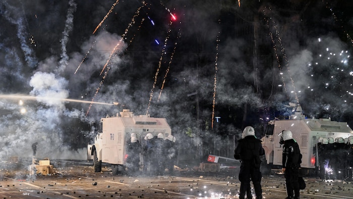 Des feux d’artifice explosent près d’un canon à eau de la police alors que des manifestants affrontent les forces antiémeutes.