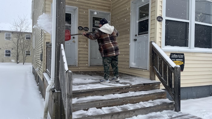 Une personne jette de la neige hors de ses marches d'escalier.