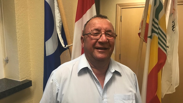 Un homme à lunettes en chemise bleu pâle.