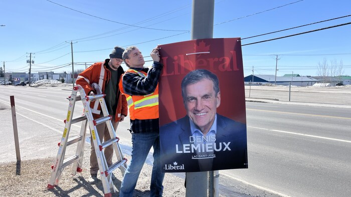 Un candidat pose ses pancartes.