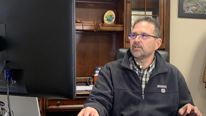 Un homme à son bureau devant un ordinateur.
