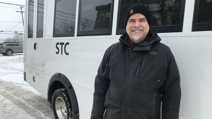 Denis Verreault pose devant un autobus.