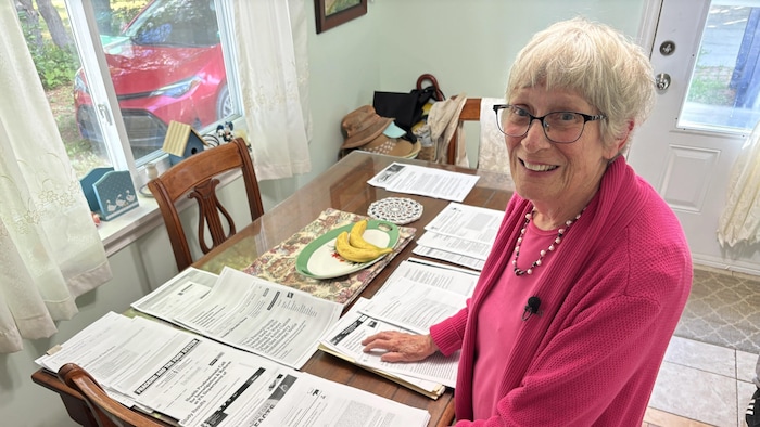 Denise Melanson avec des documents étalés sur sa table de cuisine. 