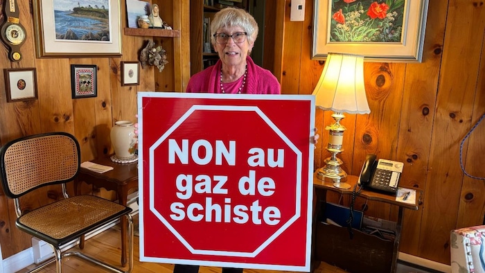Denise Melanson tenant une pancarte rouge sur laquelle il est indiqué "NON au gaz de schiste".