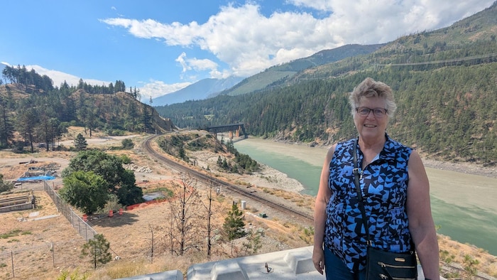 Denise O'Connor devant un cours d'eau et des montagnes.