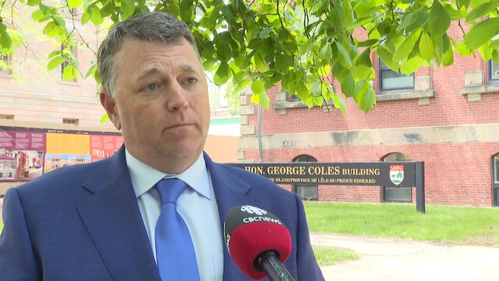 Dennis King accorde une entrevue sous un arbre devant l'édifice George Coles.