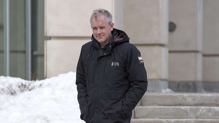 Dennis Oland marche, mains dans les poches, à l'extérieur du palais de justice de Saint-Jean.