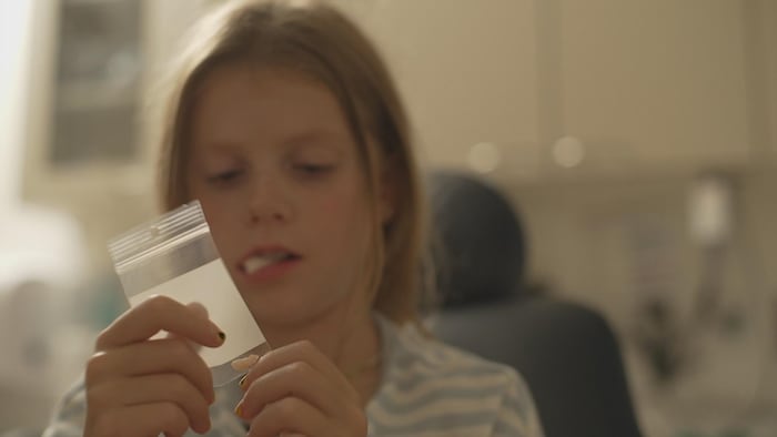 Un enfant regarde une dent placée dans un petit sac de plastique.