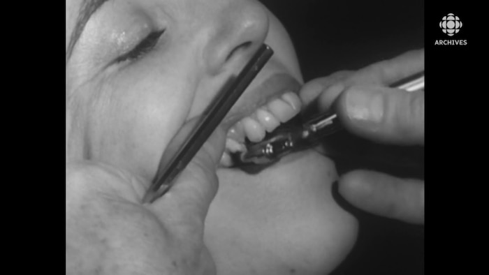 Gros plan sur des instruments de dentiste dans la bouche d’une femme.