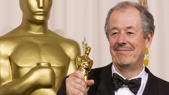 Denys Arcand sourit en tenant sa statuette.