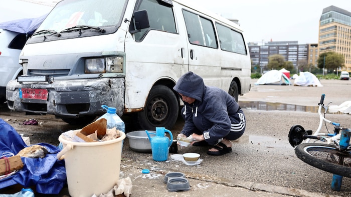 Une femme lave la vaisselle avec le peu d'eau disponible dans un campement de déplacés dans le centre de Beyrouth.
