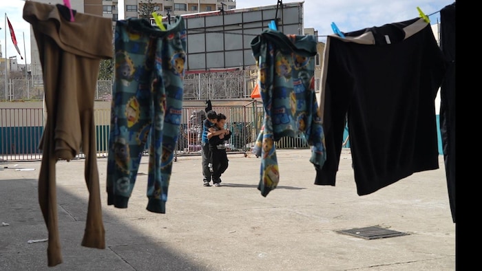 Des enfants dans une cour d'école où du linge est accroché pour sécher.