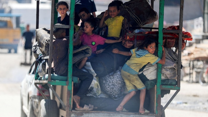 Des enfants s'entassent dans la remorque d'un véhicule.