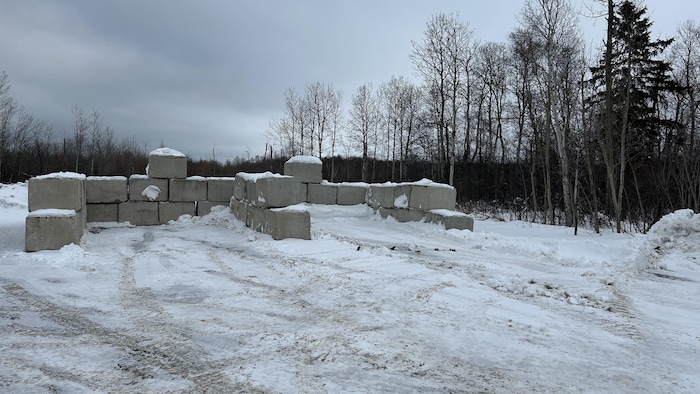 Des blocs de ciment sont empilés sur un terrain vague pour créer des enclos pour les plastiques agricoles.
