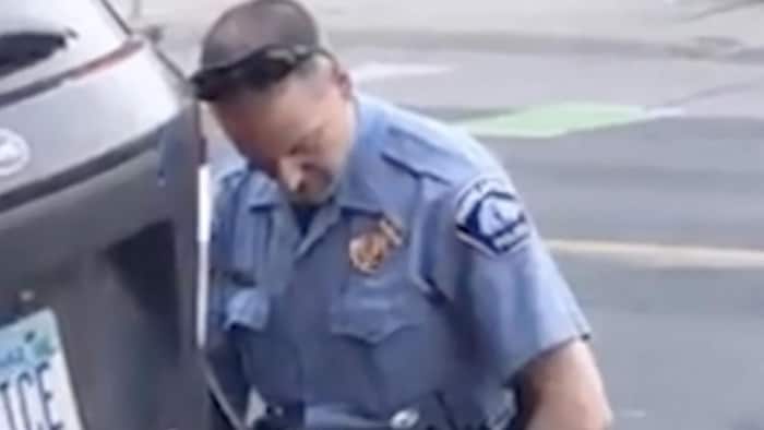 Un policier est accroupi à genou sur le cou d'un homme noir, plaqué au sol, en pleine rue.
