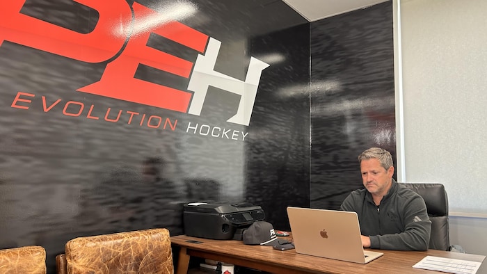 Derek Cormier dans un bureau de Pro Evolution Hockey devant un ordinateur.