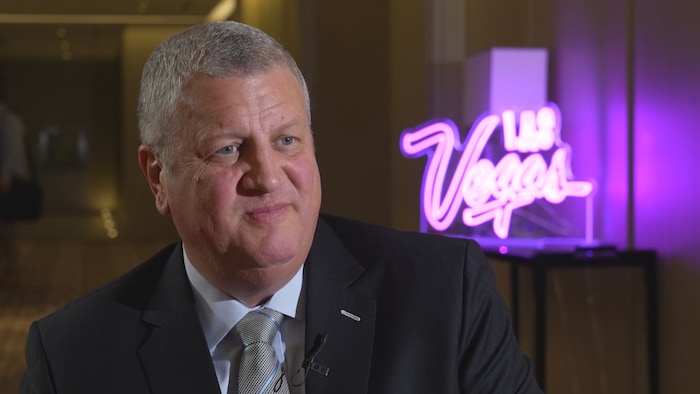 L'homme d'affaires Derek Stevens, devant un logo illuminé de Las Vegas.