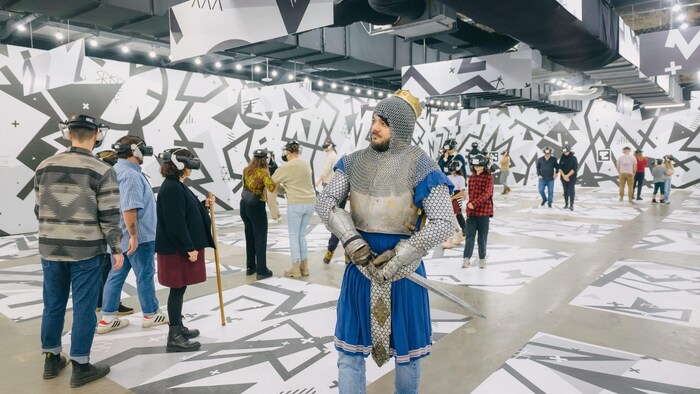 Un homme en tenue de chevalier tient une épée. 