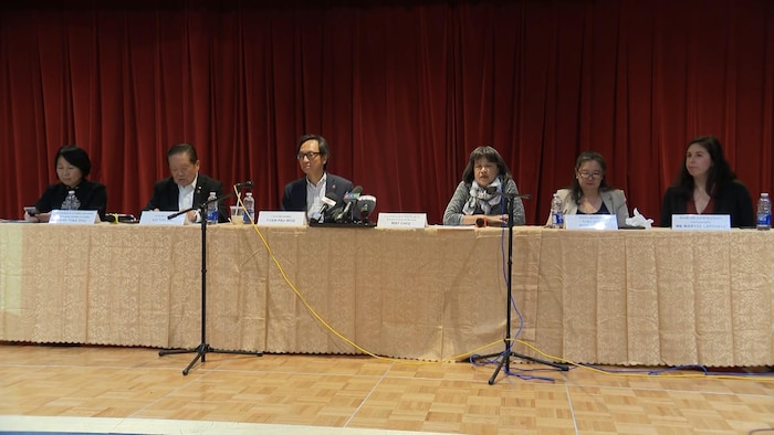 Des représentants de la communauté chinoise du Grand Montréal assis derrière une table pour un point de presse.