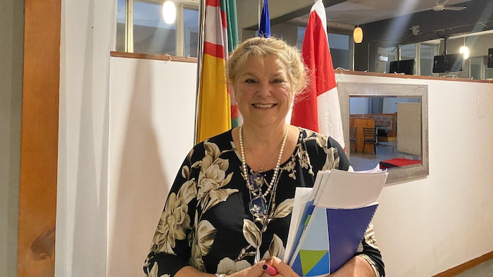 Ginette Sirois sourit devant des drapeaux.