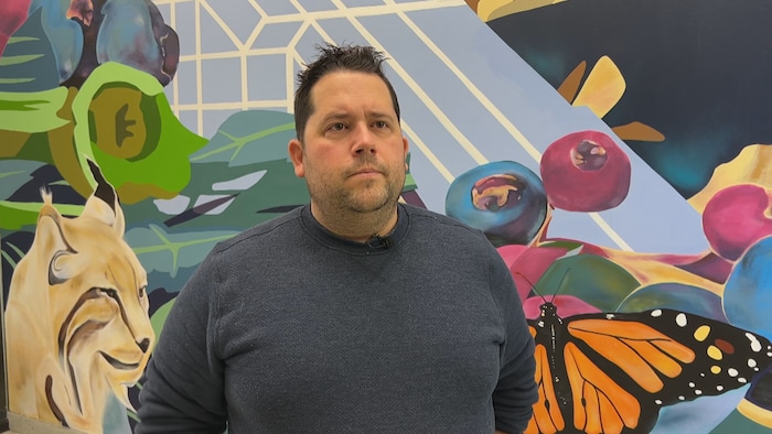 Un homme est debout devant une murale.