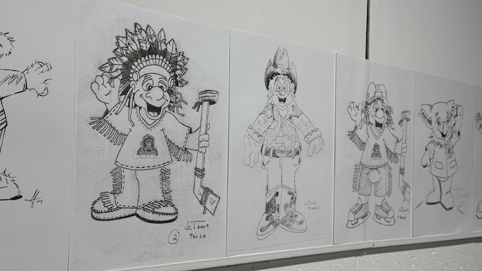 Des dessins de mascottes sont affichés sur un mur.
