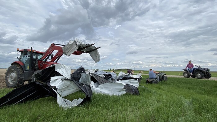 Un tracteur ramasse des débris de la grange de la famille Zinkhan, en Saskatchewan, détruite par le passage d'une tornade le 27 mai 2023.