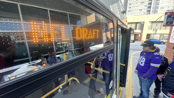 Un autobus identifié pour le repêchage de la NFL ouvre ses portes à des gens avec des chandails d'équipes de football.